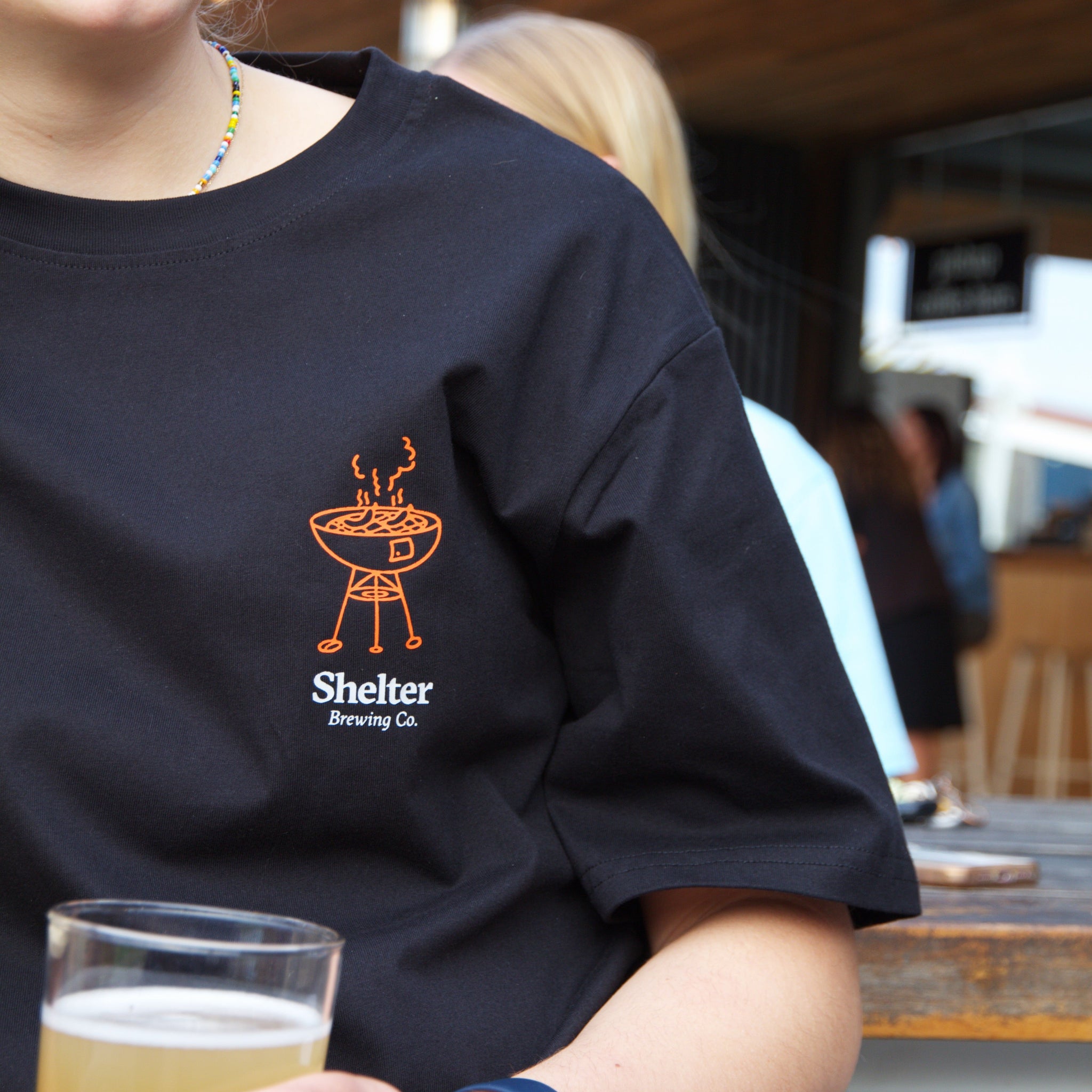Shelter worker wearing new Summer BBQ tee and holding Pale Ale